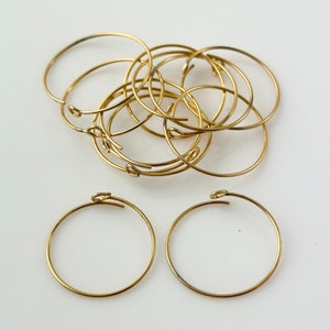 May include: A set of ten gold-toned metal hoops with a hinged clasp. The hoops are approximately 2 inches in diameter.