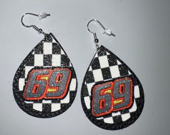 May include: A pair of teardrop-shaped earrings with a black and white checkered pattern. Each earring features the number "69" in gray with orange and yellow accents. The earrings have silver-colored ear wires.