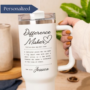 May include: White insulated tumbler with a handle, featuring the text "Difference Maker" in a script font, along with a definition. The word "Personalized" is on a blue banner. The tumbler is held by a person.