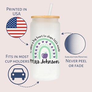 Puede incluir: Un vaso blanco con un dise&ntilde;o de arco&iacute;ris verde y morado, una manzana roja y el texto "Se necesita un gran coraz&oacute;n para moldear las peque&ntilde;as mentes Sra. Johnson". El vaso tiene una tapa de madera y una pajita.