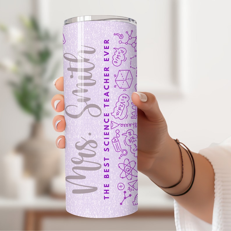 May include: A light purple stainless steel travel mug with the text "Mrs. Smith THE BEST SCIENCE TEACHER EVER" in silver. The mug has purple science-themed doodles. A thoughtful gift for a science teacher.