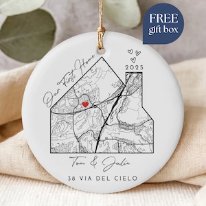 May include: White ceramic ornament with a map design in black and a red heart. The text "Our First Home," "Tom & Julia," and "38 VIA DEL CIELO" are printed on the ornament. The year "2025" is also displayed. A gold string is attached for hanging.