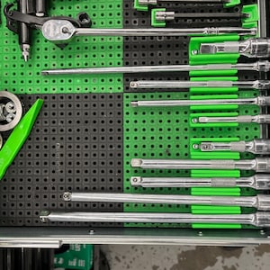 May include: A collection of tools, including ratchets, sockets, and extensions, neatly organized in a green and black tool tray. The tools are made of metal and have green accents. A green pry bar with the word "GRIP" is also visible.