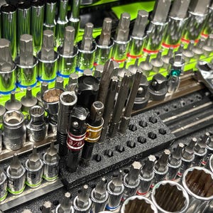 May include: A collection of chrome steel socket bits and adapters organized in a black foam tray. The set includes various hex, Torx, and spline bits with red and yellow color-coded rings on two adapters labeled 3/8 and 1/4 respectively.