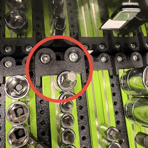 May include: Close-up of a tool organizer with various sockets and bits. The organizer is black with green dividers. Several sockets and bits are visible, including hex and star-shaped heads. The tools are arranged neatly, suggesting a focus on organization and efficiency.