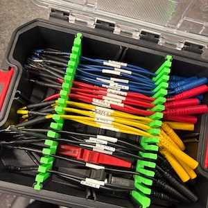 May include: A black toolbox with a clear lid, filled with an assortment of colored electrical wires. The wires are organized with green dividers. The wires are red, yellow, blue, and black, with white labels.
