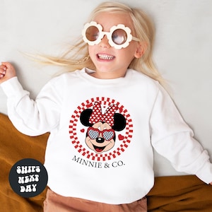 a little girl wearing a minnie mouse shirt