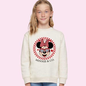 a little girl wearing a minnie mouse sweatshirt