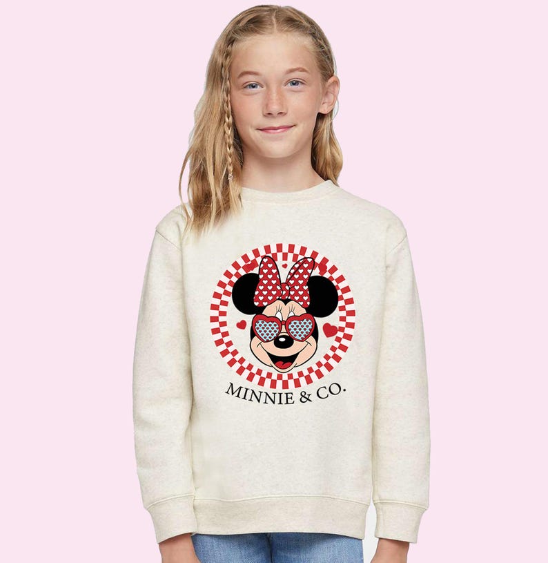 a little girl wearing a minnie mouse sweatshirt