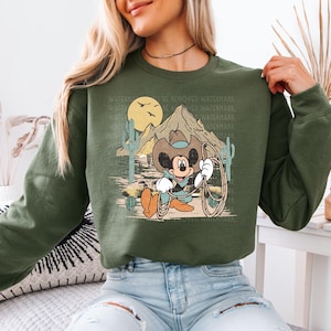 a woman wearing a green sweatshirt with mickey mouse on it