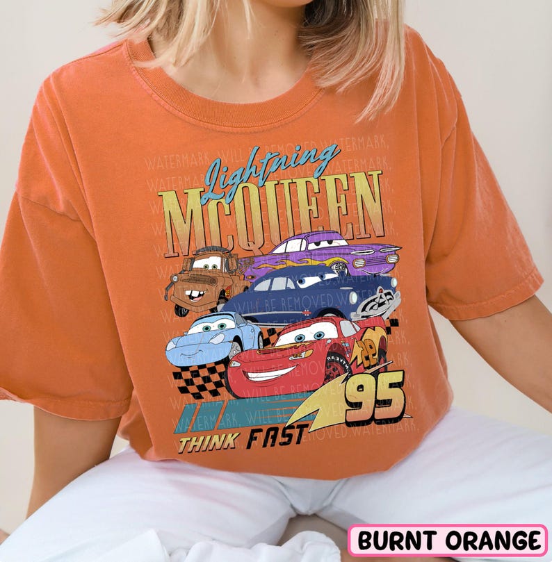 a woman wearing an orange shirt with cars on it