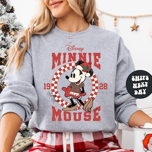 A woman wearing a gray sweatshirt with a graphic of Minnie Mouse and the text "Disney MINNIE MOUSE" printed on it.