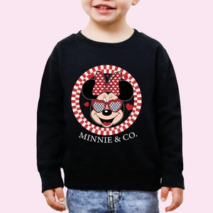 a young boy wearing a minnie mouse sweatshirt