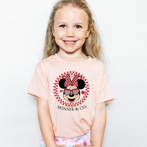 a little girl wearing a minnie mouse shirt
