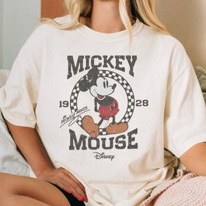 A white t-shirt with a graphic of Mickey Mouse and text that reads " Mickey Mouse" and "Disney".