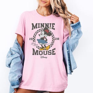 a woman wearing a pink minnie mouse t - shirt
