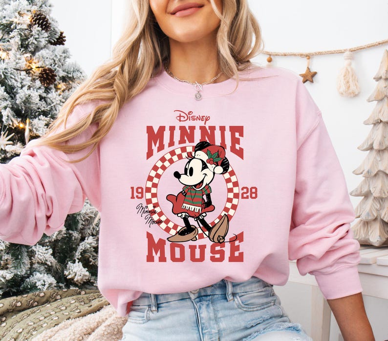 A woman wearing a pink sweatshirt with a cartoon image of Minnie Mouse and the text "Disney Minnie Mouse" printed on it.