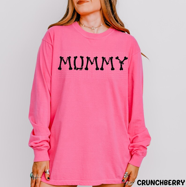 A woman wearing a pink long-sleeved shirt with the word "MUMMY" printed on it.