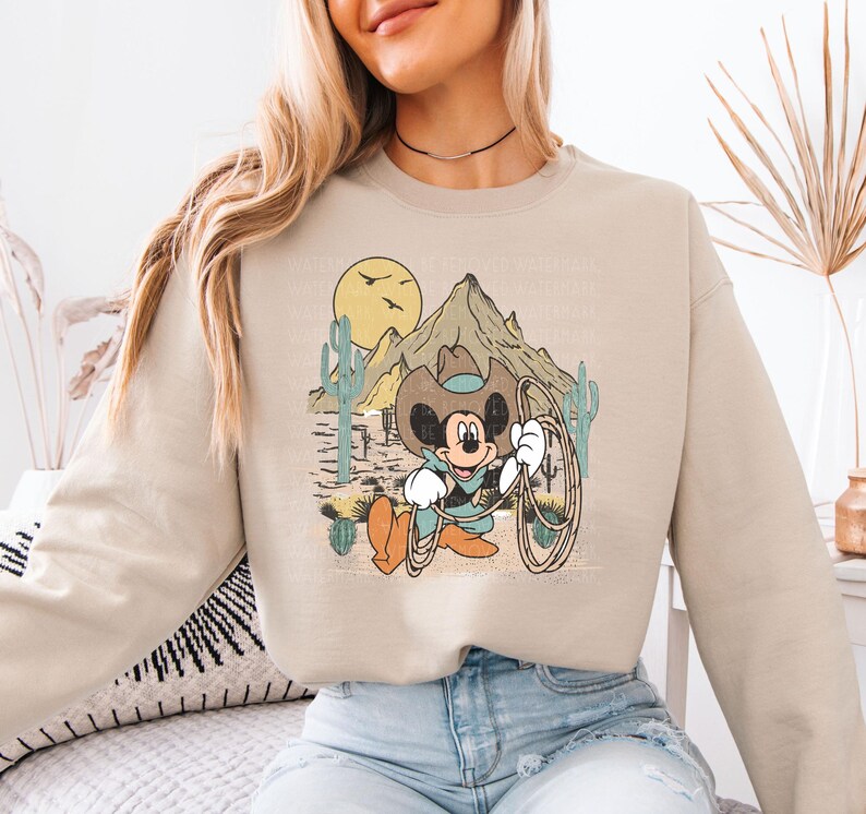 a woman sitting on a bed wearing a mickey mouse sweatshirt