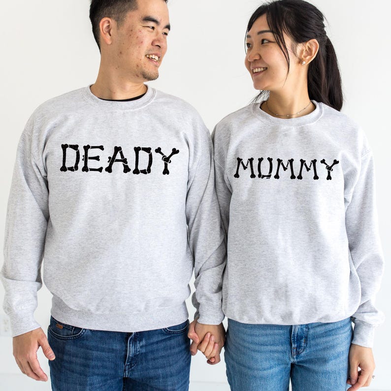 A man and a woman standing side by side, both wearing gray sweatshirts with the word "DEADY" printed on them.