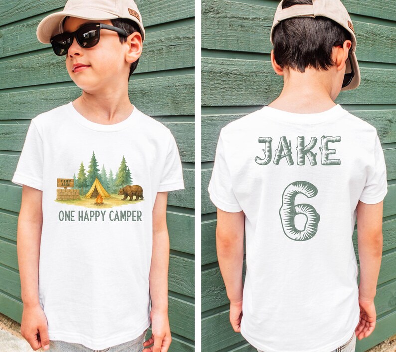 a young boy wearing a white shirt with a camp scene on it