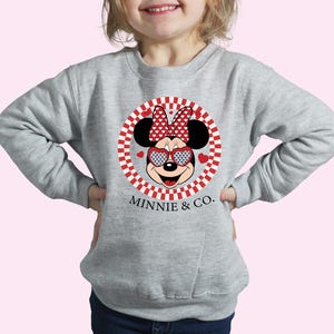 a little girl wearing a minnie mouse sweatshirt
