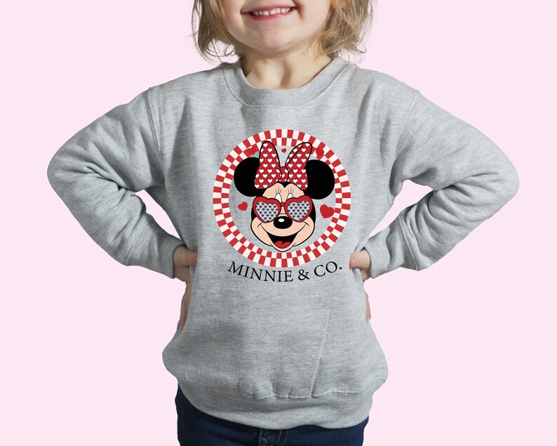 a little girl wearing a minnie mouse sweatshirt
