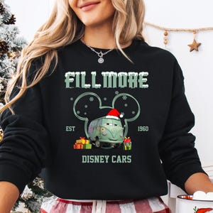 A woman wearing a black sweatshirt with a graphic design featuring a cartoon character and text related to Disney Cars.