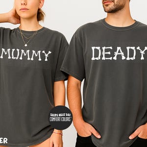 A man and a woman wearing matching t-shirts with the word "MUMMY" and "DEADY" printed on them, posing together.