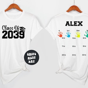 May include: White t-shirts with a graduation theme. One shirt displays "Class Of 2039" with a graduation cap graphic. The other shirt has the name "ALEX" above colorful handprints and grade levels from K to 12th grade.