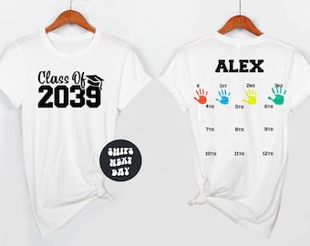 May include: White t-shirts with a graduation theme. One shirt displays "Class Of 2039" with a graduation cap graphic. The other shirt has the name "ALEX" above colorful handprints and grade levels from K to 12th grade.