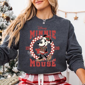 A woman wearing a gray sweatshirt with a graphic of Mickey Mouse and the text "Disney MINNIE MOUSE" printed on it.
