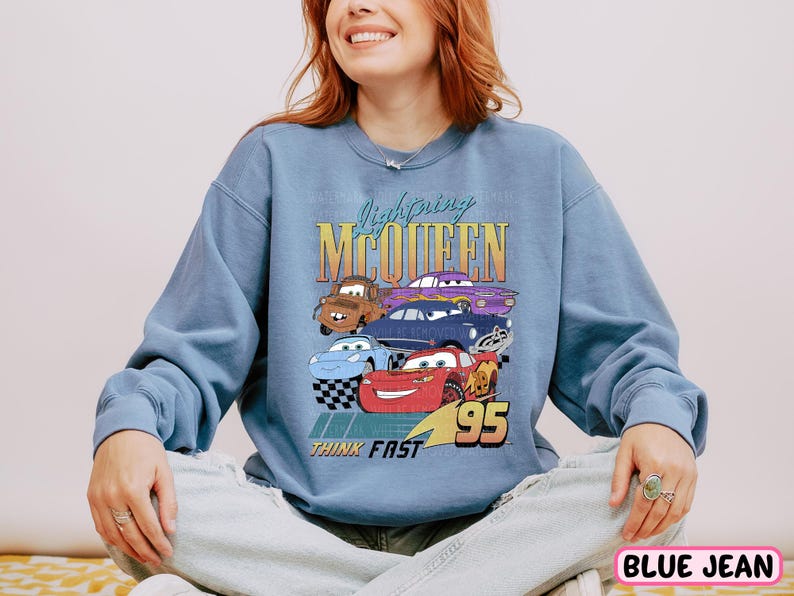a woman sitting on a bed wearing a blue sweatshirt