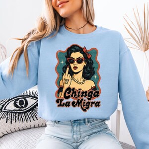 a woman wearing a blue sweatshirt with a picture of a woman wearing sunglasses