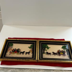 May include: Two framed pictures with gold trim and black mats. Each picture depicts a horse-drawn carriage with passengers in a park setting.