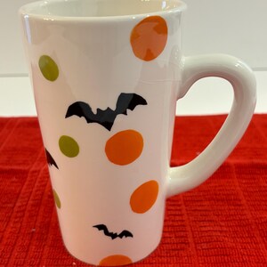 Halloween Mug, decorated with bats and orange, yellow and green circles. 7 inches tall