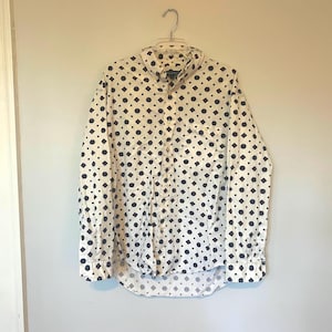 May include: A white long-sleeve button-down shirt with a black geometric pattern.