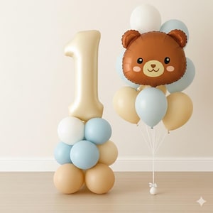 May include: A festive balloon arrangement featuring a large number one balloon in a cream color, and a cluster of balloons in white, light blue, and tan. A brown bear-shaped balloon is also included, perfect for a first birthday celebration.