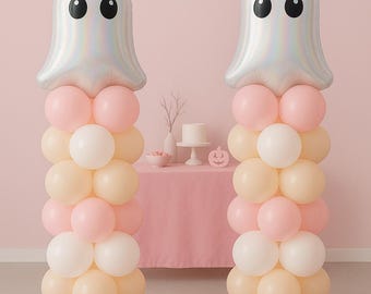 May include: Two balloon columns with a Halloween theme. Each column has a silver ghost-shaped balloon at the top with black eyes. The columns are made of pink, white, and peach-colored balloons, perfect for a festive party.