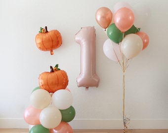 Könnte beinhalten: Eine festliche Luftballon-Dekoration zum ersten Geburtstag. Enthält orangefarbene Kürbisballons, einen großen Ballon mit der Zahl eins und einen Strauß aus rosa, grünen und weißen Ballons. Ideal für eine Party zum Thema Herbst.