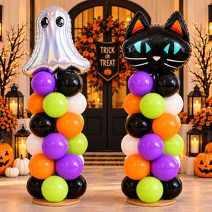 May include: Two balloon columns featuring a holographic ghost foil balloon on the left and a black cat foil balloon on the right. Each column is constructed from stacked purple, orange, lime green, black, and white latex balloons on a base.