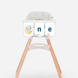 May include: A white high chair with wooden legs and a blue and white banner that says "one" with a cute elephant illustration.