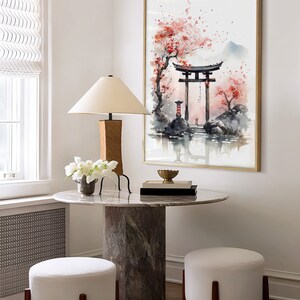 May include: A watercolor painting of a Japanese garden scene with a red torii gate, cherry blossoms, and a mountain in the background. The painting is framed in gold and hangs on a white wall.