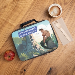 May include: A black lunch bag with a zipper closure. The bag features a colorful illustration of a merman sitting on a rock with a speech bubble that says "I'm on a seafood diet. I see food, and I eat it!"