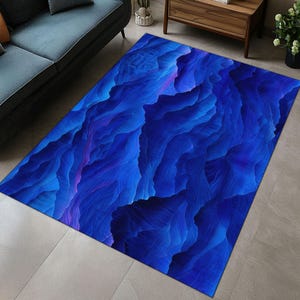 May include: Abstract blue and purple rug with a swirling, textured pattern. The rug has a contemporary design and would add a modern touch to any room.