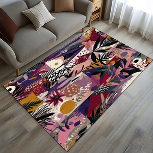 Puede incluir: Una alfombra rectangular con un colorido dise&ntilde;o floral abstracto. La alfombra presenta una mezcla de formas geom&eacute;tricas y elementos bot&aacute;nicos rosas, morados, amarillos y negros, creando un patr&oacute;n vibrante y art&iacute;stico. La alfombra est&aacute; colocada sobre un suelo de madera.