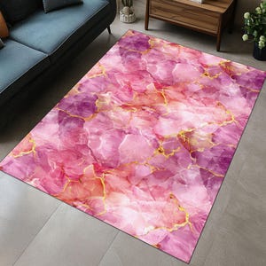 May include: Pink and gold marble patterned area rug with a abstract design.