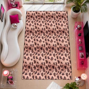 May include: A rectangular rug with a leopard print design. The rug has a light brown base with dark brown spots. The rug is positioned on a light-coloured floor, and is surrounded by furniture and decor.