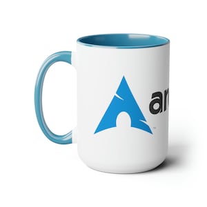 Könnte beinhalten: Eine weiße Keramiktasse mit blauem Rand und Henkel. Die Tasse zeigt ein blaues und schwarzes Arch Linux Logo.