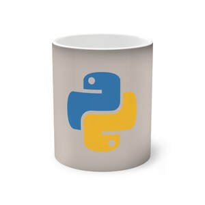 Op de afbeelding: Een witte keramische mok met een grijze achtergrond en een geel en blauw Python-logo.